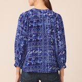 Woman wearing a blue patterned blouse with a beige background