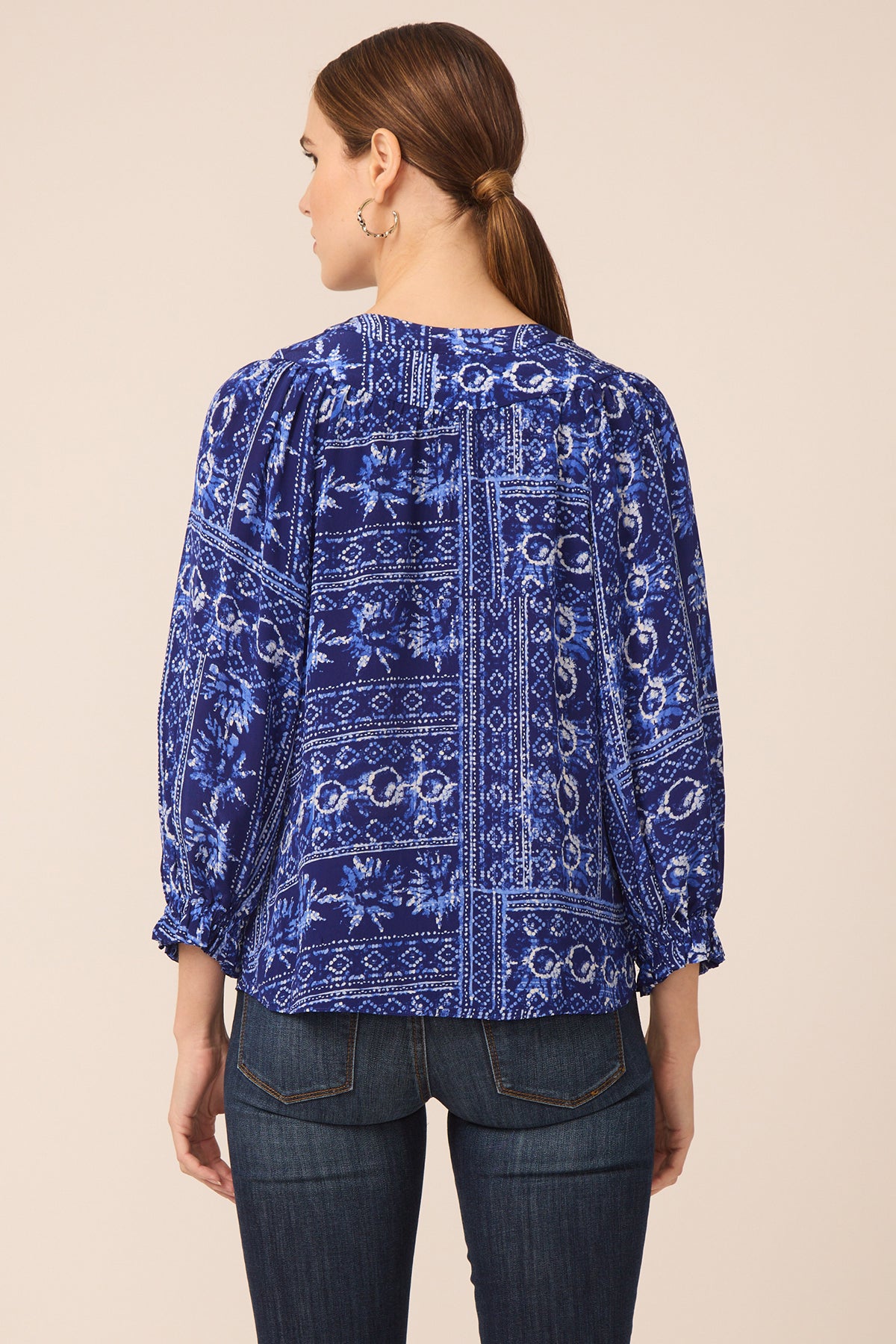 Woman wearing a blue patterned blouse with a beige background