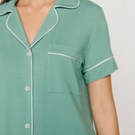 Green nightshirt with white piping on a plain background