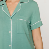Green nightshirt with white piping on a plain background