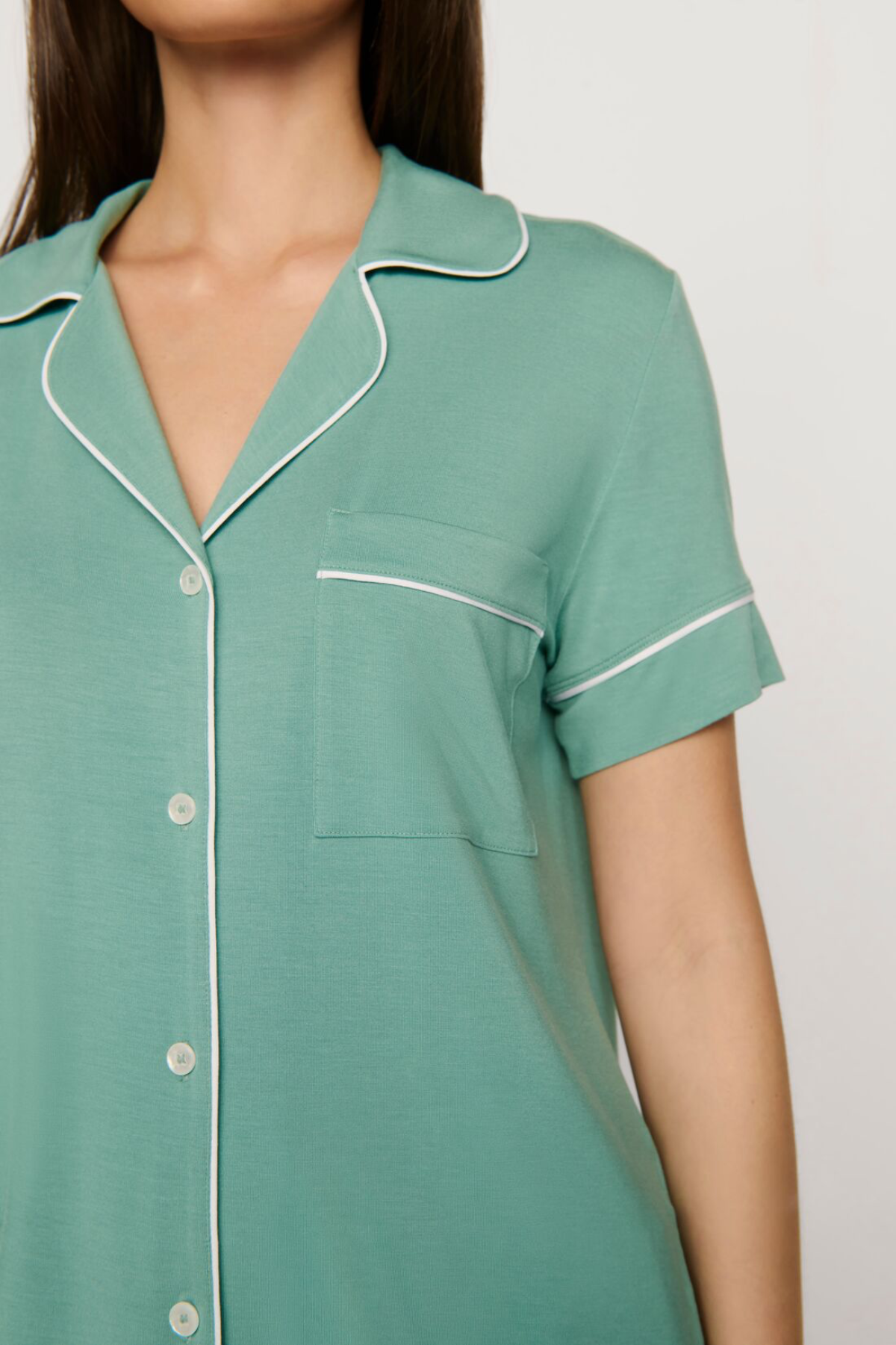 Green nightshirt with white piping on a plain background