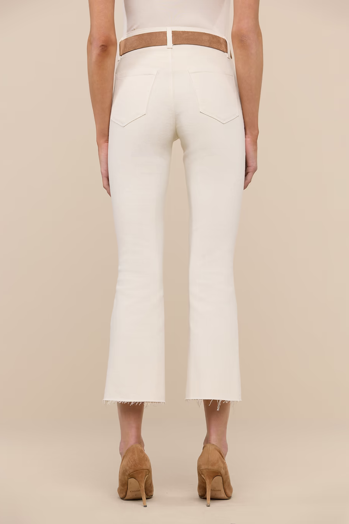 Person wearing white pants with a brown belt on a beige background