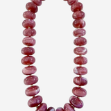 A chunky beaded necklace made of polished oval beads in a dusty rose pink color, separated by small gold spacer beads and finished with a gold clasp, shown on a light gray background.