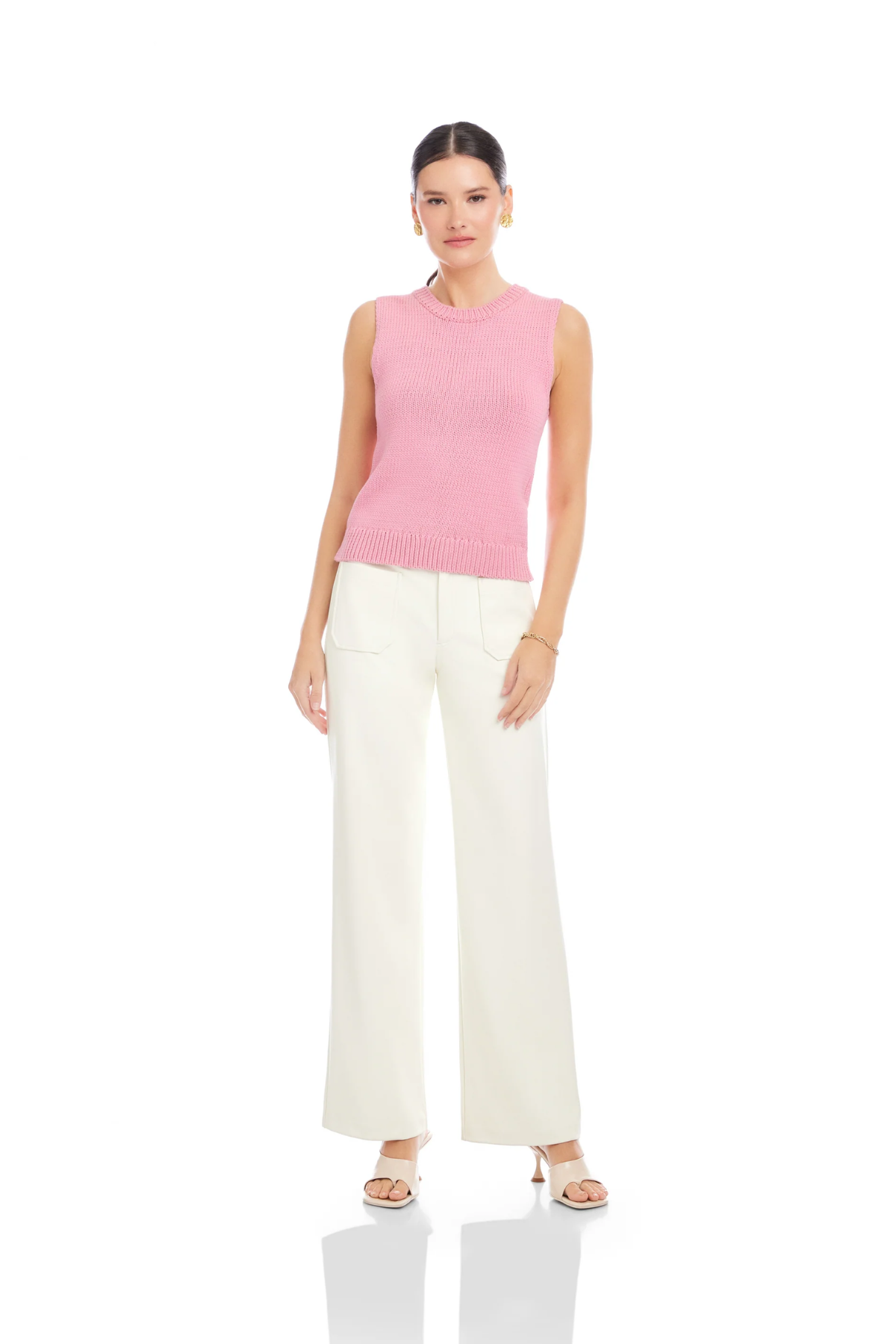 Woman wearing a pink sleeveless top and white pants on a white background