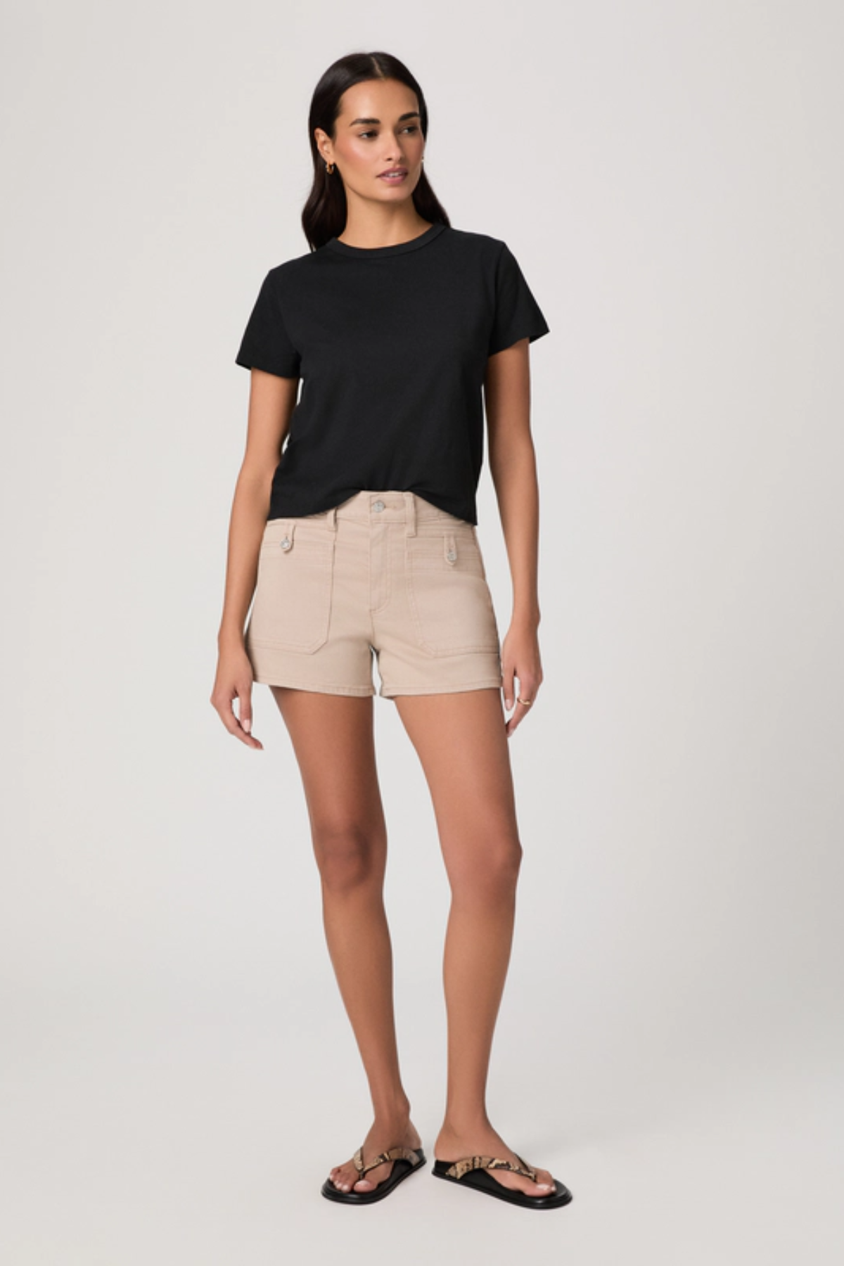 Woman wearing a black t-shirt and beige shorts on a white background