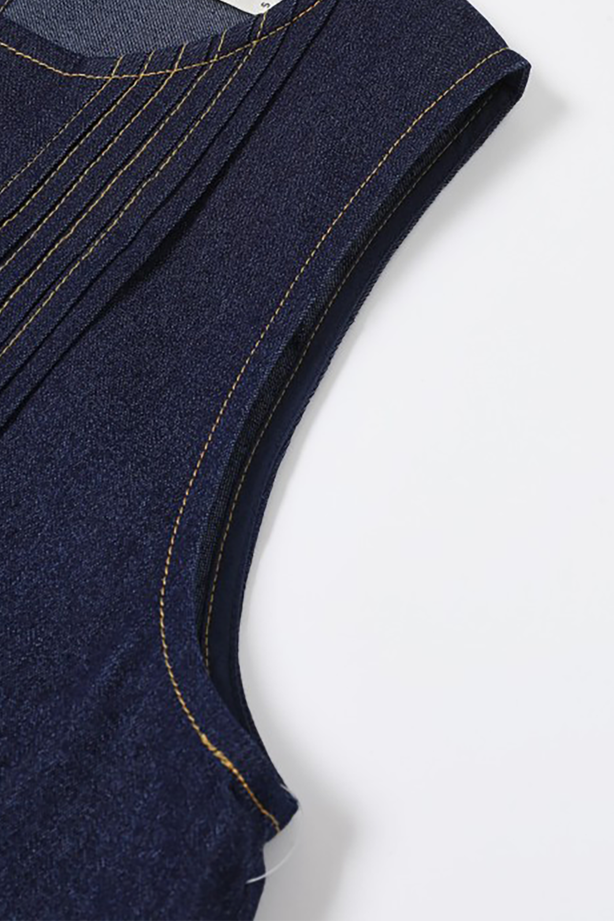 Close-up of a navy blue garment with gold stitching on a white background