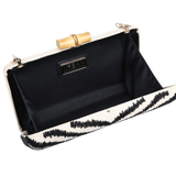 Black clutch with white interior and gold accents on a white background
