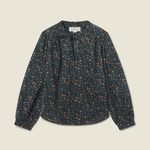 A long-sleeve blouse with a dark navy blue base and a dense orange and yellow floral print, laid flat against a light beige background.