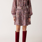 Person wearing a patterned dress with a belt and red knee-high boots on a white background