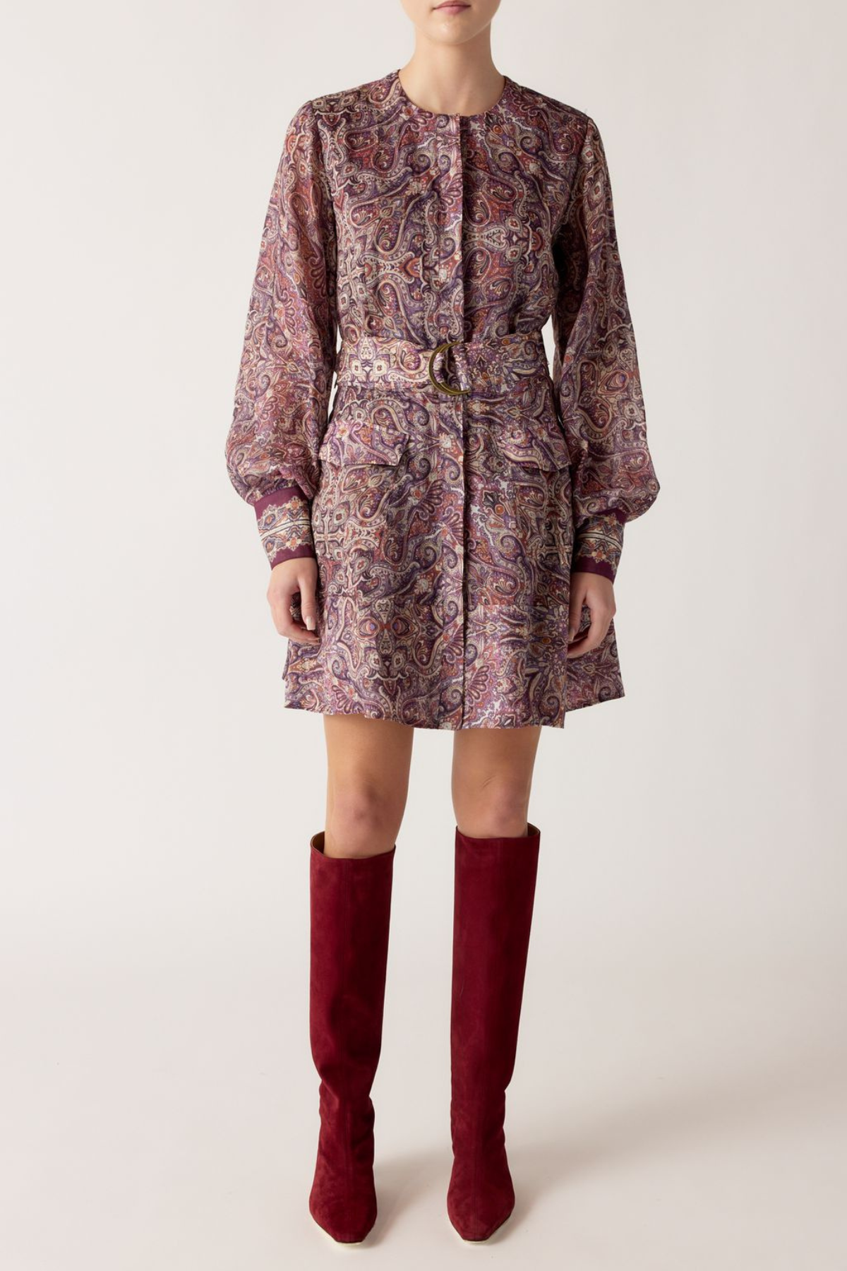 Person wearing a patterned dress with a belt and red knee-high boots on a white background