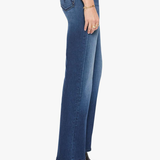 A side profile view of a model wearing blue high-waisted flare jeans, paired with a white top and black pointed-toe ankle boots, against a plain white background.