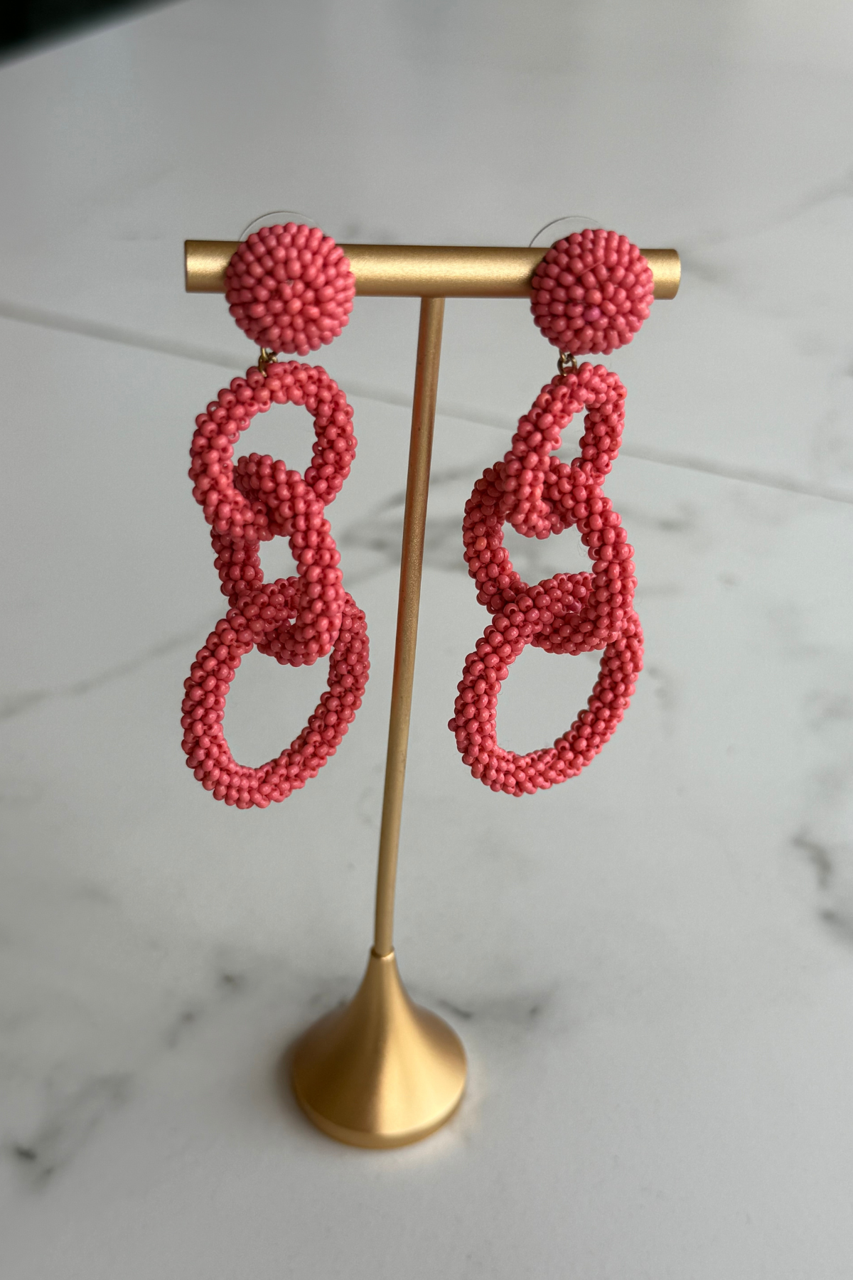 \coral pink linked drop earrings featuring three open circular shapes in a lightweight statement design.