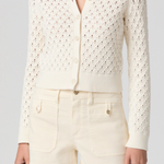 Person wearing a white lace cardigan and shorts on a gray background