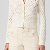 Person wearing a white lace cardigan and shorts on a gray background