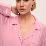 Woman wearing a pink pajama set with white trim against a light background