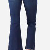 A person wearing dark blue flare jeans with frayed hems and tan flat sandals, shown from the back against a light gray background.