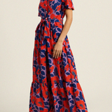 Woman wearing a red and blue floral dress on a beige background