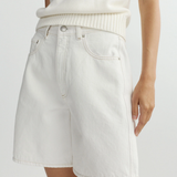 Person wearing  white denim shorts and white sweater on a plain background