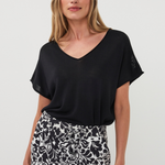 Woman wearing a black top and patterned skirt on a white background