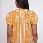 Model wearing a sleeveless orange printed blouse with a relaxed silhouette.