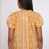 Model wearing a sleeveless orange printed blouse with a relaxed silhouette.
