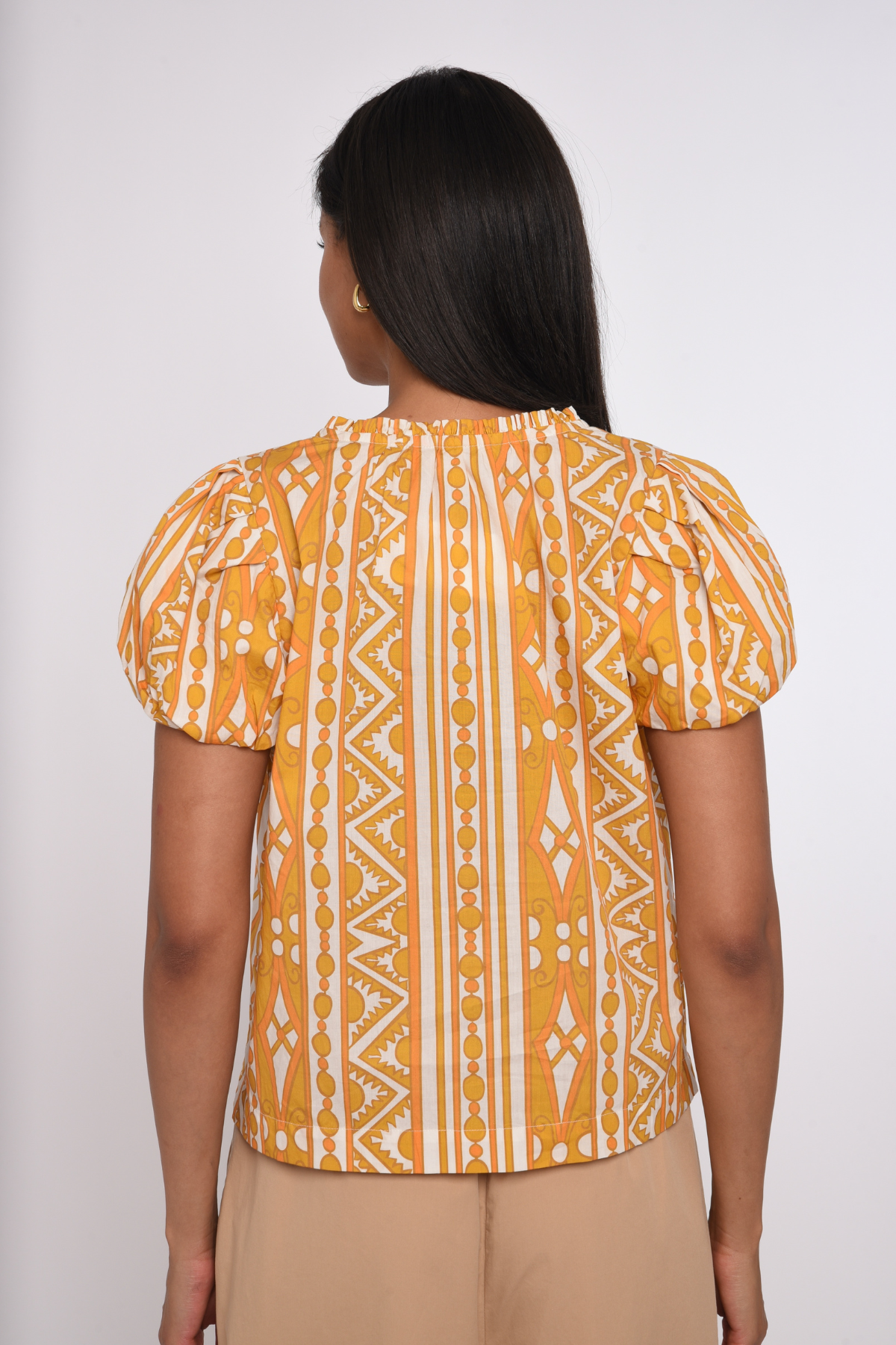 Model wearing a sleeveless orange printed blouse with a relaxed silhouette.