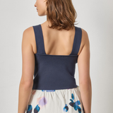 Woman wearing a navy top and floral skirt on a plain background