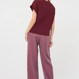 A woman shown from the back wearing a short-sleeve maroon top and mauve wide-leg pinstripe trousers against a plain white studio background.