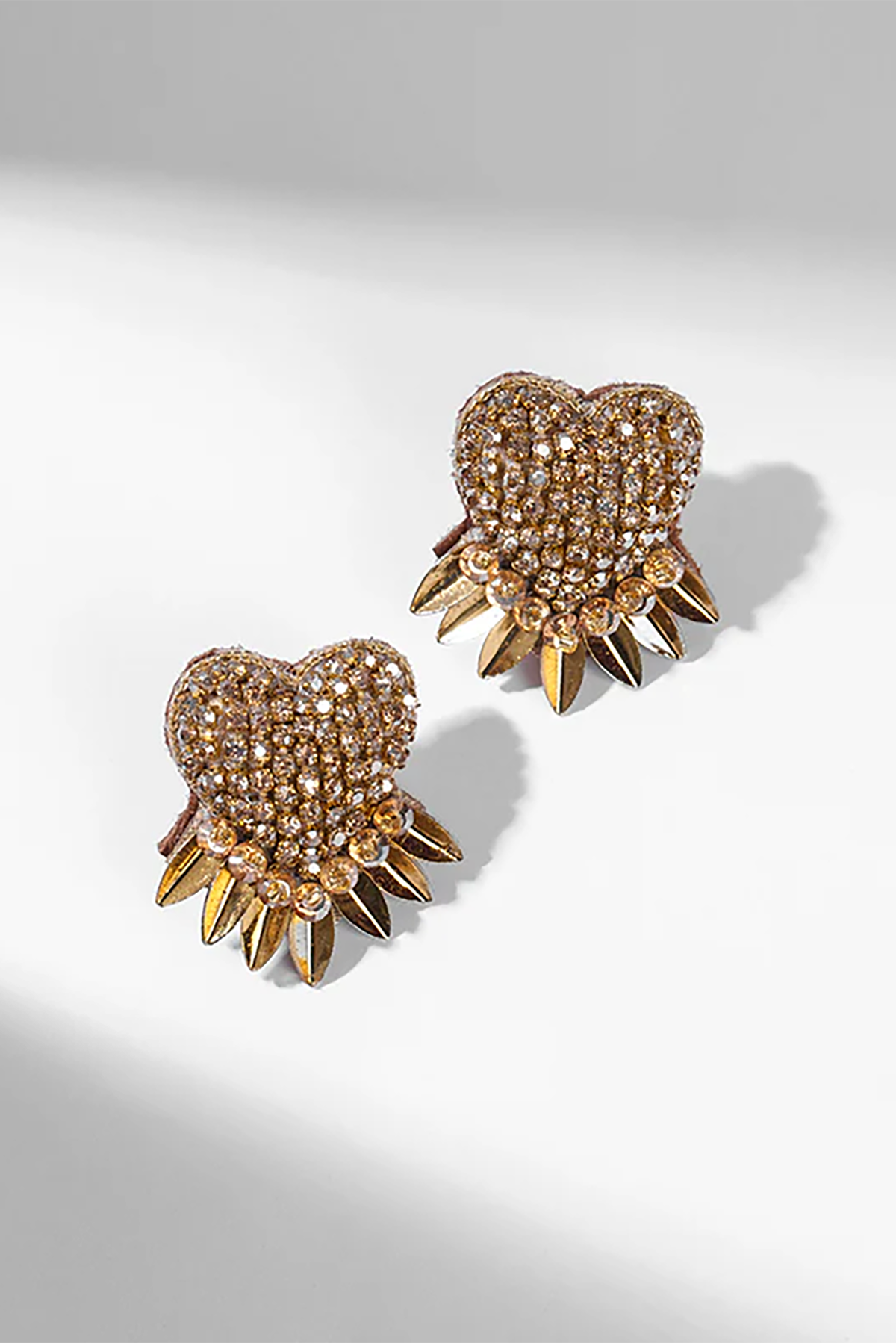 Heart-shaped earrings with spike details on a light gray background