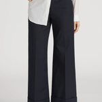 Person wearing navy wide-leg pants with a white shirt on a plain background