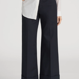 Person wearing navy wide-leg pants with a white shirt on a plain background