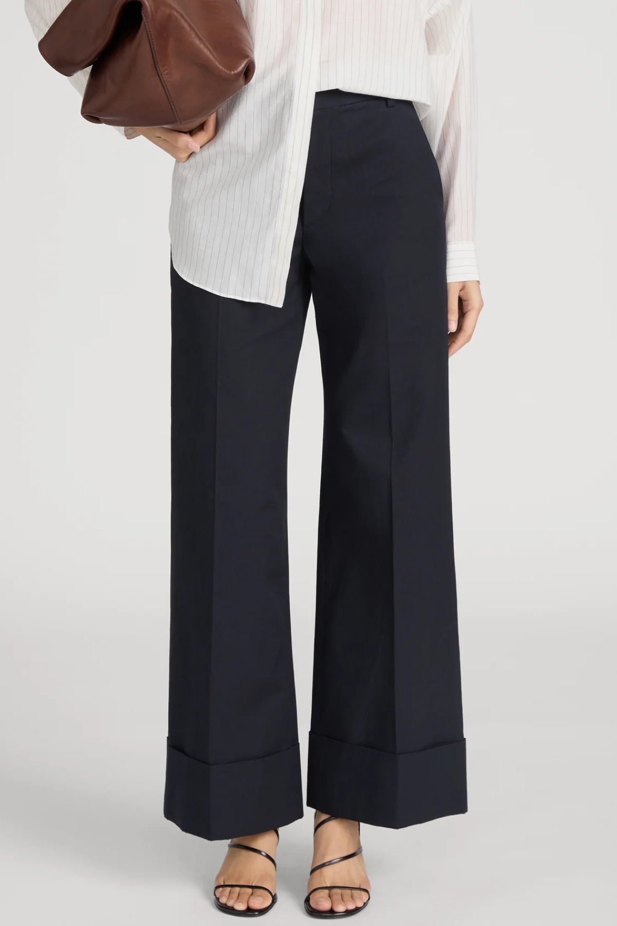 Person wearing navy wide-leg pants with a white shirt on a plain background