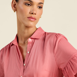 Woman wearing a pink blouse against a beige background