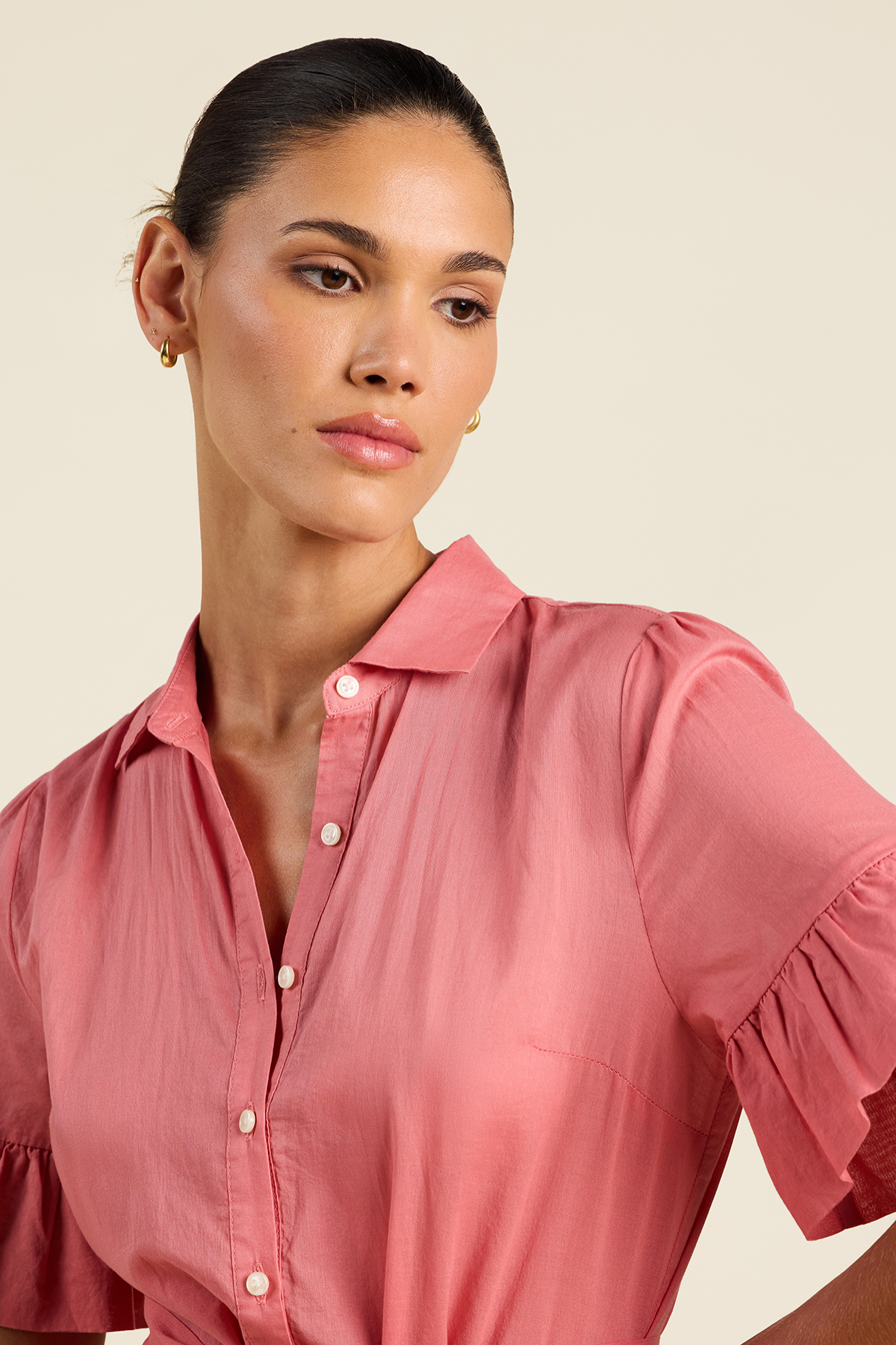 Woman wearing a pink blouse against a beige background