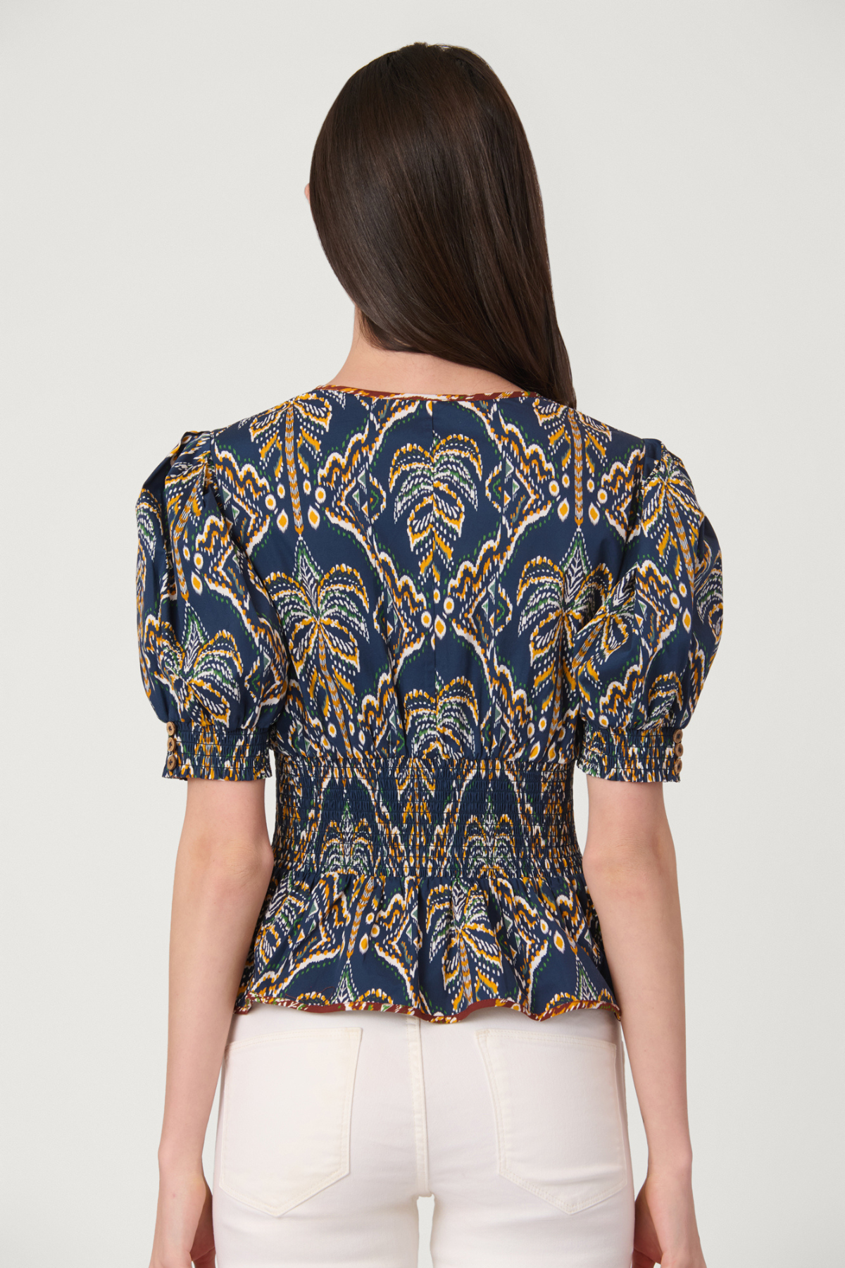 Woman wearing a blue and yellow patterned top on a white background