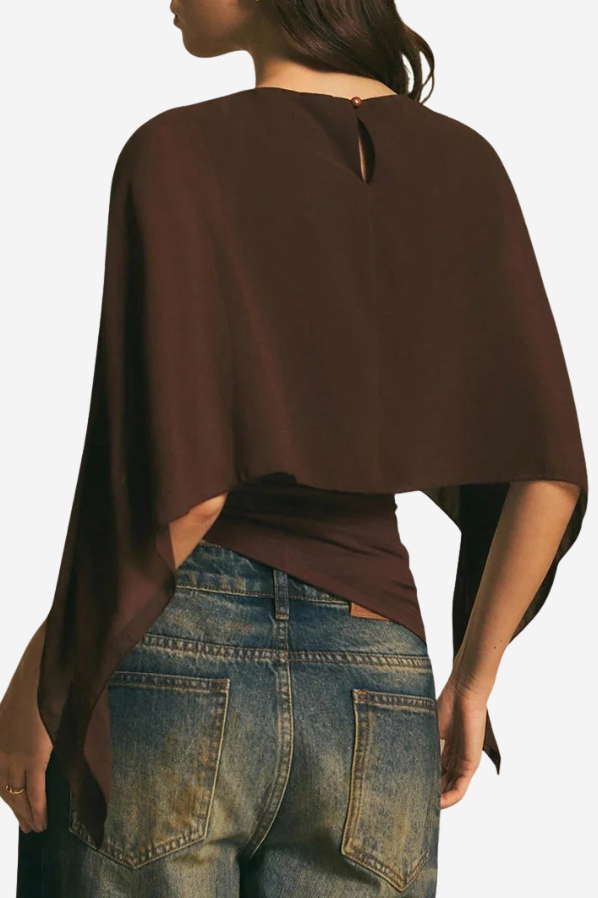 A woman shown from the back wearing a dark brown draped poncho-style top with a small keyhole cutout at the neckline, paired with blue jeans.
