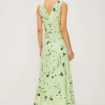 Woman wearing a light green dress with floral pattern on a white background