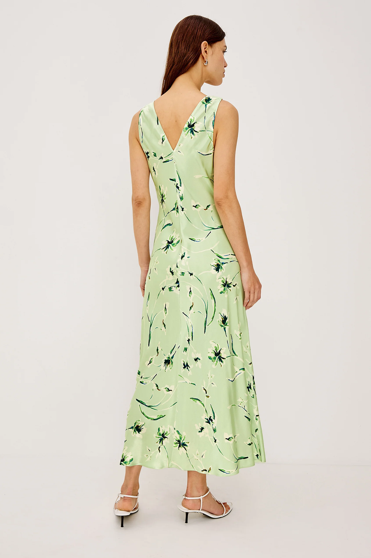 Woman wearing a light green dress with floral pattern on a white background
