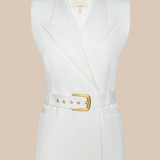 White sleeveless blazer with a gold belt on a beige background