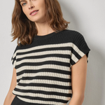 Woman wearing a black and white striped sweater against a plain background