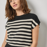 Woman wearing a black and white striped sweater against a plain background