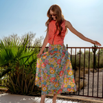Woman in a colorful dress standing by a pool with a desert landscape in the background