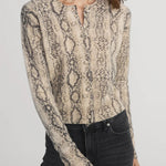 Woman wearing a snake print blouse with long sleeves on a plain background