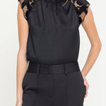 Black top with lace details on sleeves worn by a model against a white background