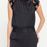 Black top with lace details on sleeves worn by a model against a white background