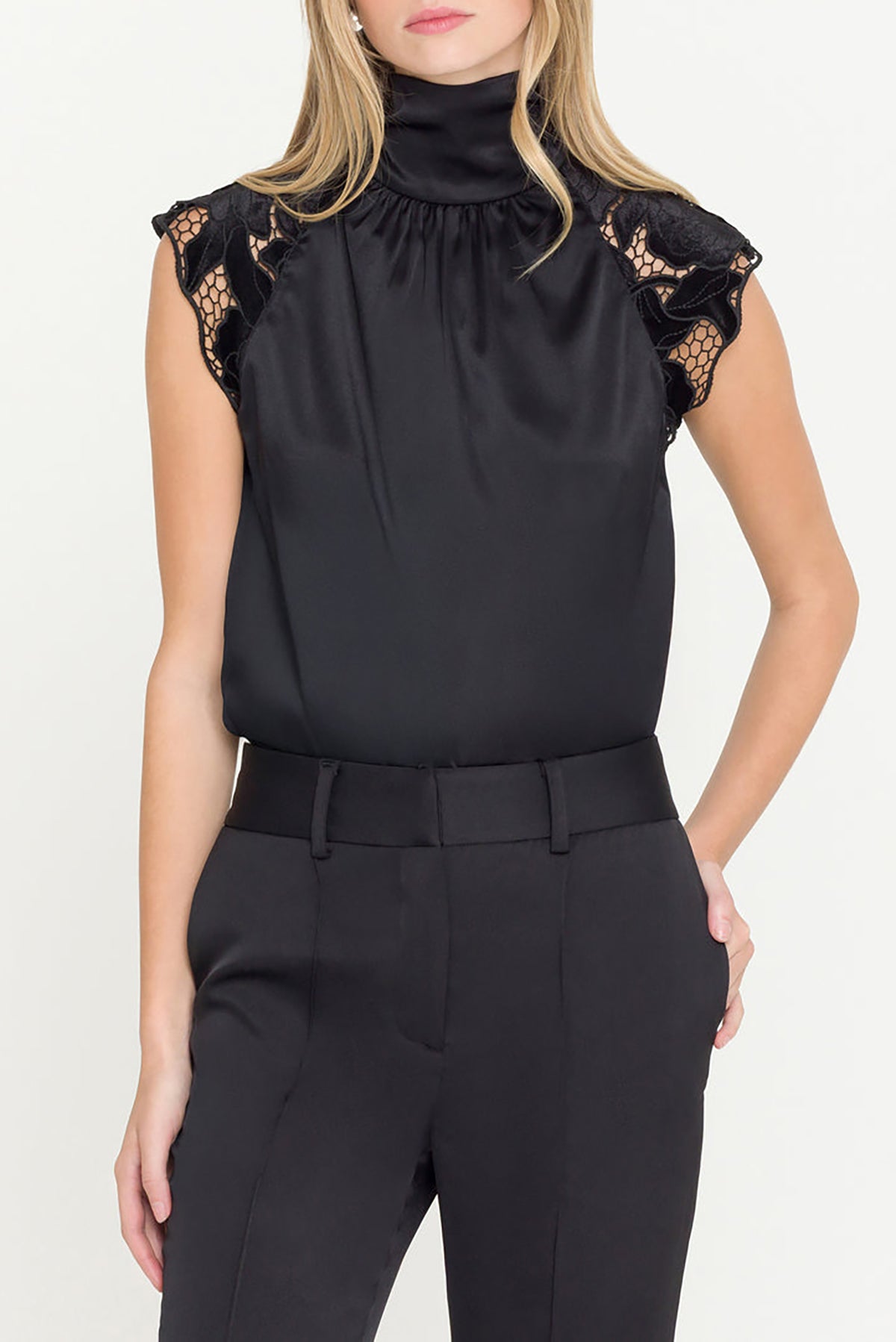 Black top with lace details on sleeves worn by a model against a white background