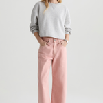 Woman wearing a gray sweater and pink pants on a white background