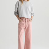 Woman wearing a gray sweater and pink pants on a white background