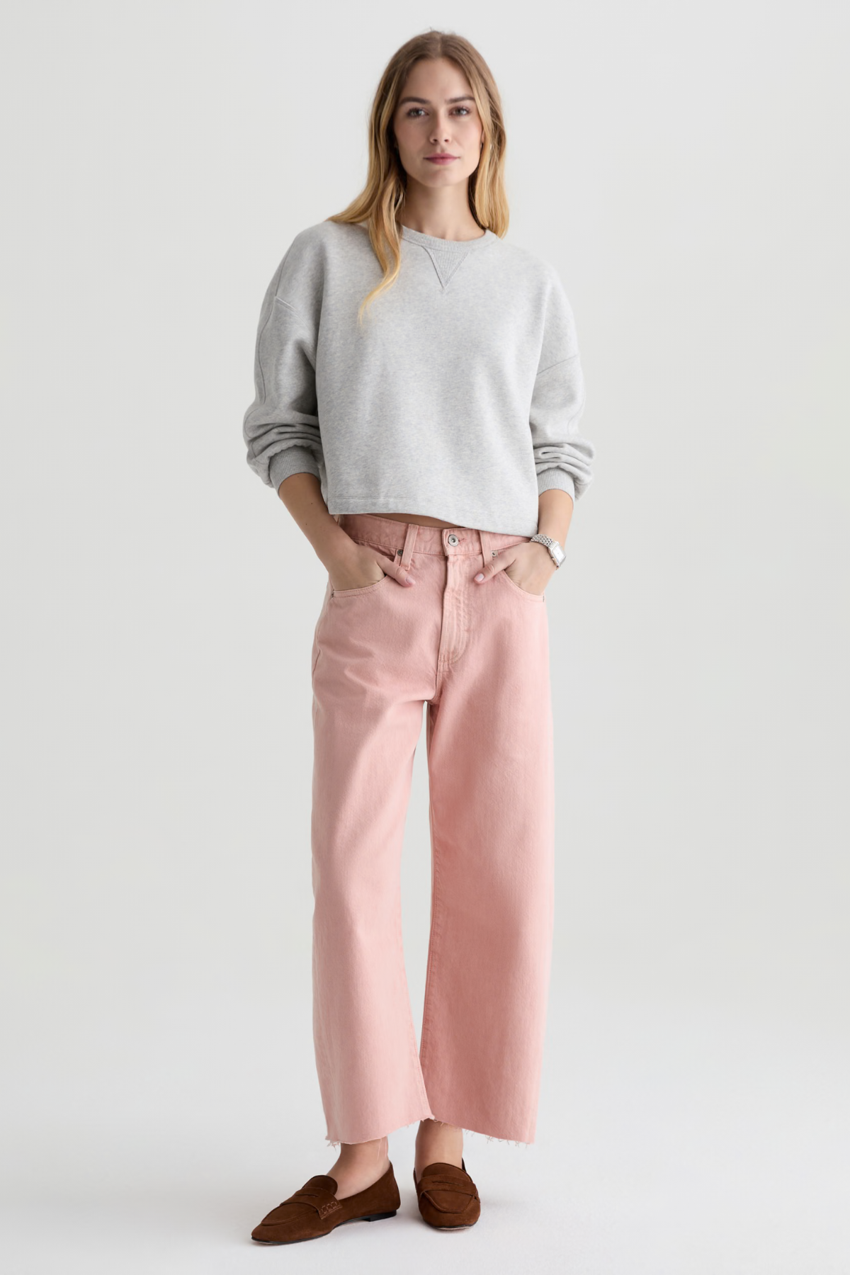 Woman wearing a gray sweater and pink pants on a white background
