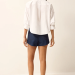 Person wearing a white shirt and navy shorts on a plain background